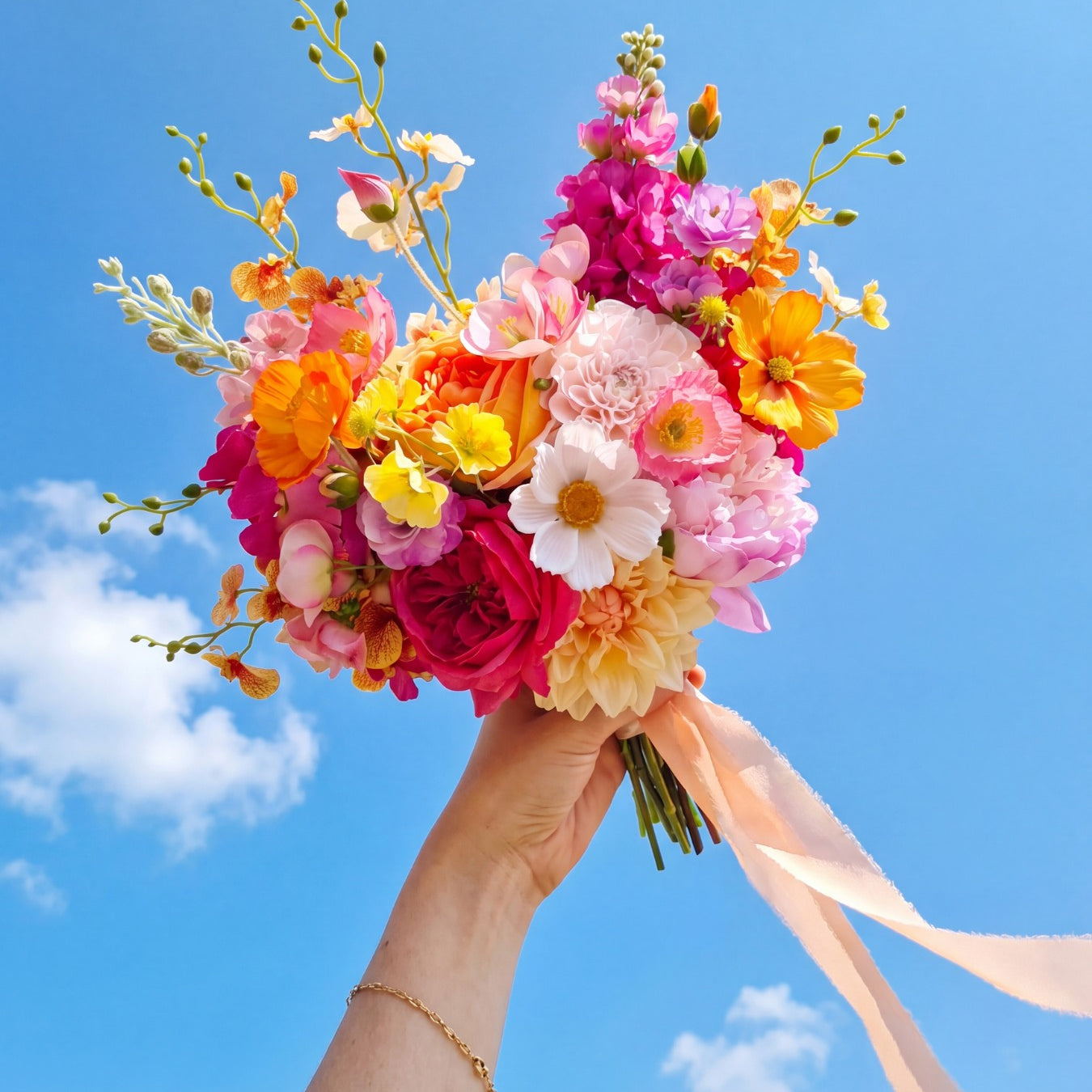 Bouquet of colorful flowers held against a blue sky